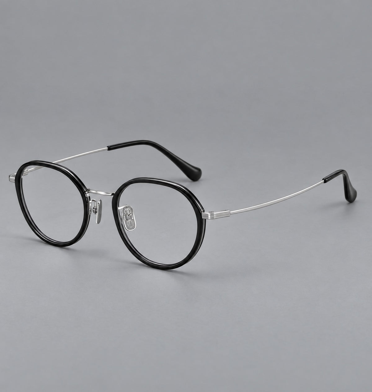 Rounded eyeglasses in acetate and titanium with gently arched brows and engraved metal temples in Black / Silver, three quarter view