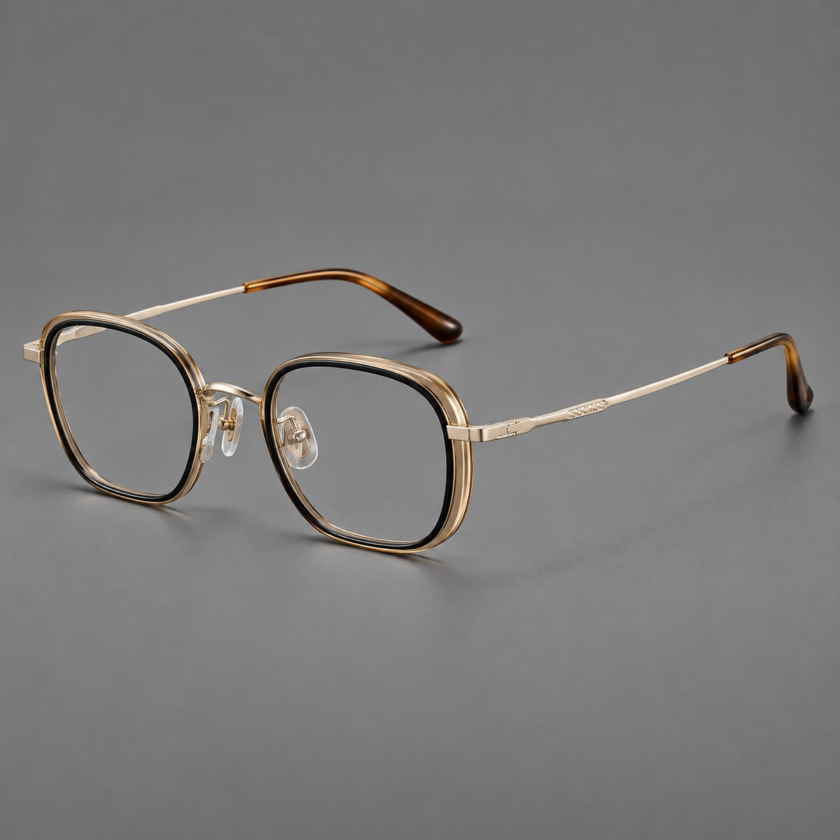 Rounded square eyeglasses in acetate and titanium with an arched bridge and engraved temples in Black and Clear Tea / Light Gold, three quarter view