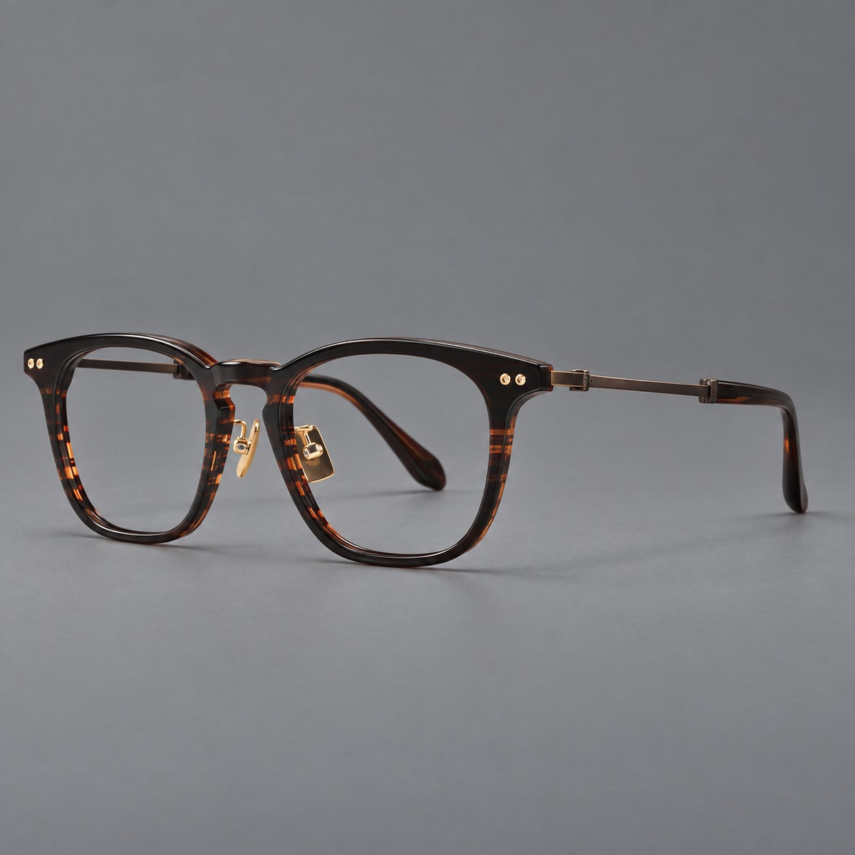 Retro acetate and titanium eyeglasses with gently squared rims and circular metal hinges in Striped Dark Brown / Antique Bronze, three quarter view