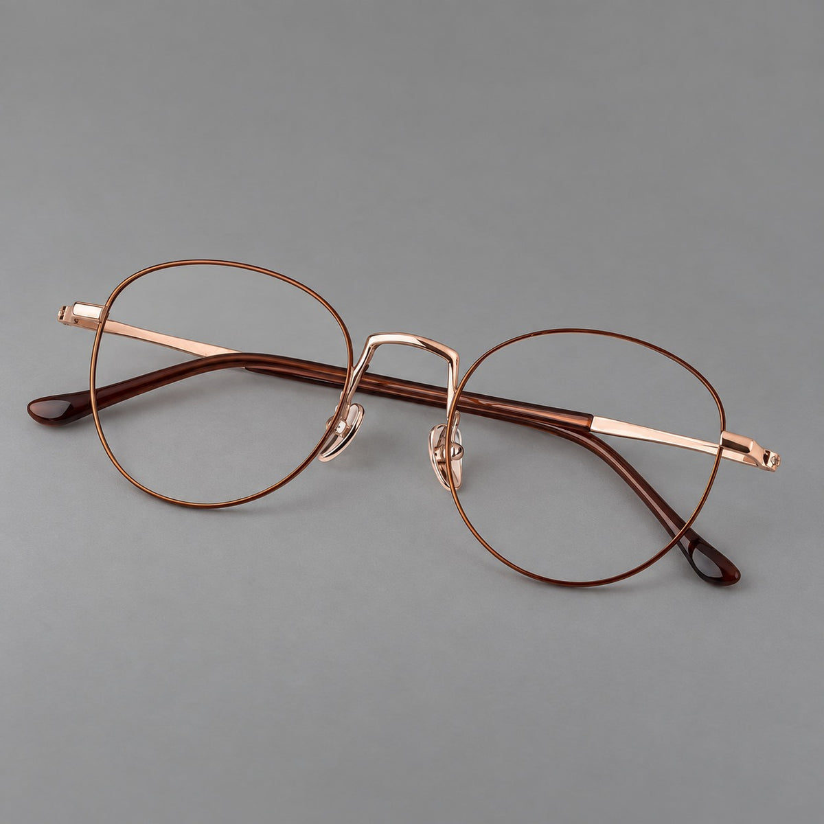 Retro round titanium glasses with a raised bridge and smooth corner shoulders in Brown and Rose Gold, three quarter view