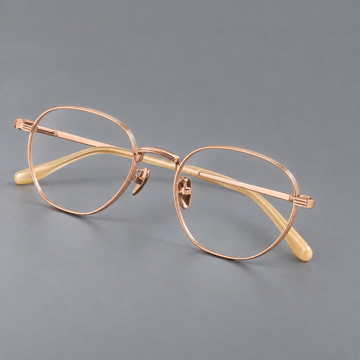 Retro panto titanium glasses with a curved bridge and fine parallel rim grooves in Rose Gold, three quarter view