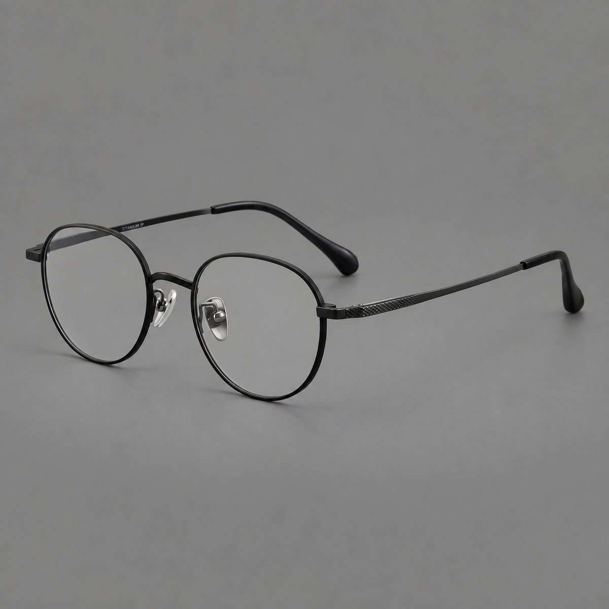 Compact round titanium glasses with an arched bridge and textured temple accents in Black, three quarter view