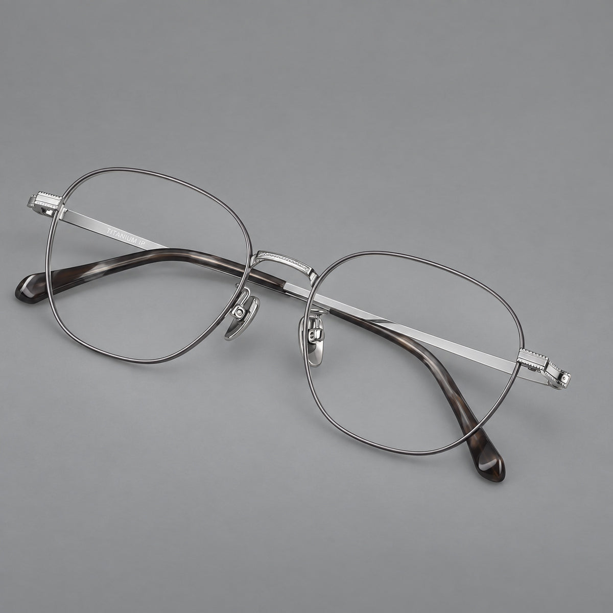 Retro panto titanium glasses with stepped corners and finely engraved temples in Grey and Silver, three quarter view