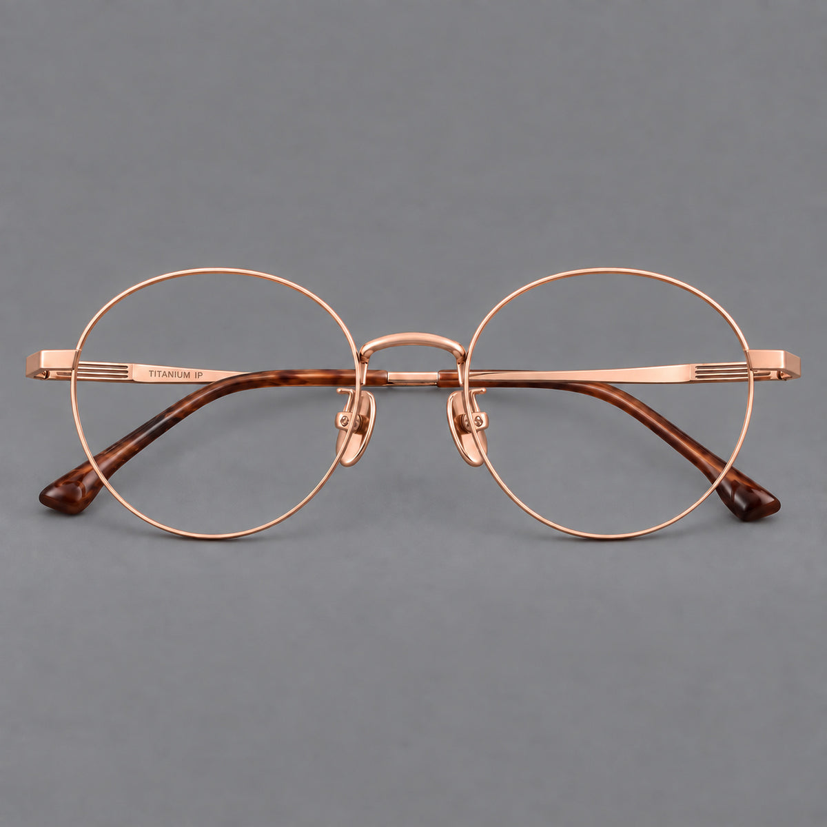Classic circular titanium glasses with a raised bridge and lined temple accents in Rose Gold, front view