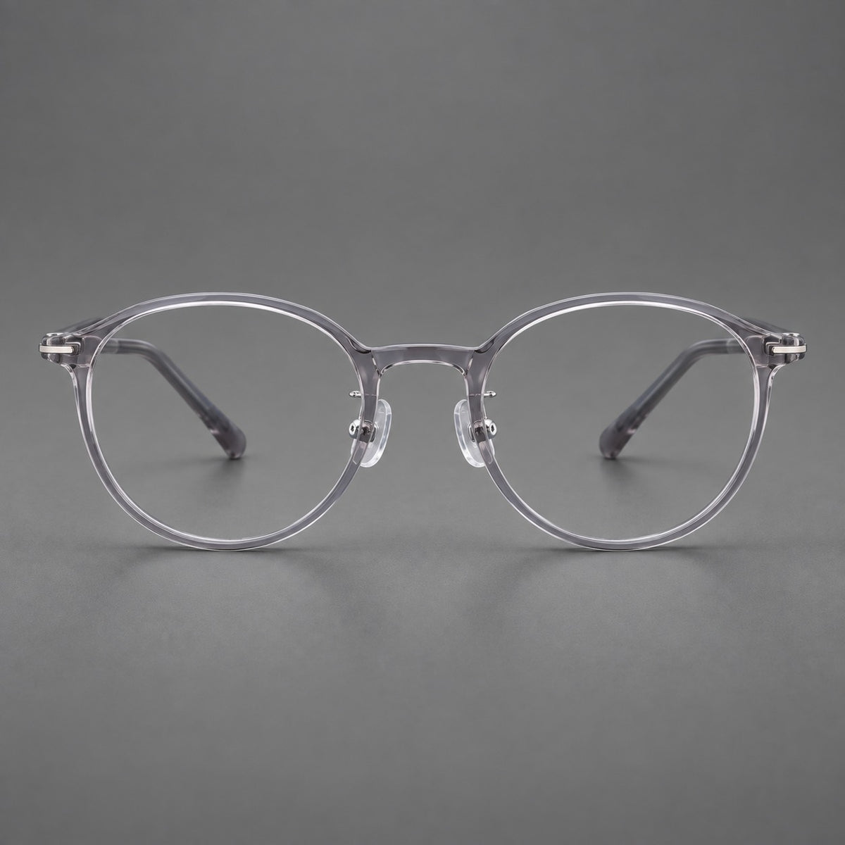 Compact round plastic eyeglasses with gently lifted corners and clear nose pads in Clear Grey, front view