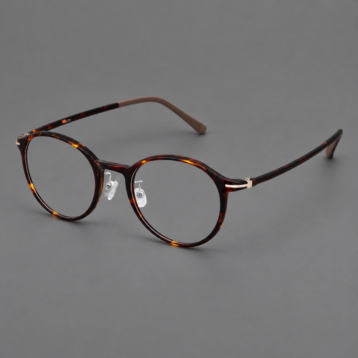 Compact round plastic eyeglasses with gently lifted corners and clear nose pads in Tortoiseshell, three quarter view