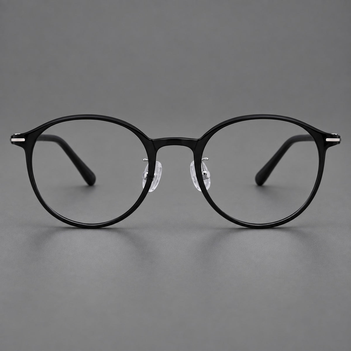 Compact round plastic eyeglasses with gently lifted corners and clear nose pads in Glossy Black, front view
