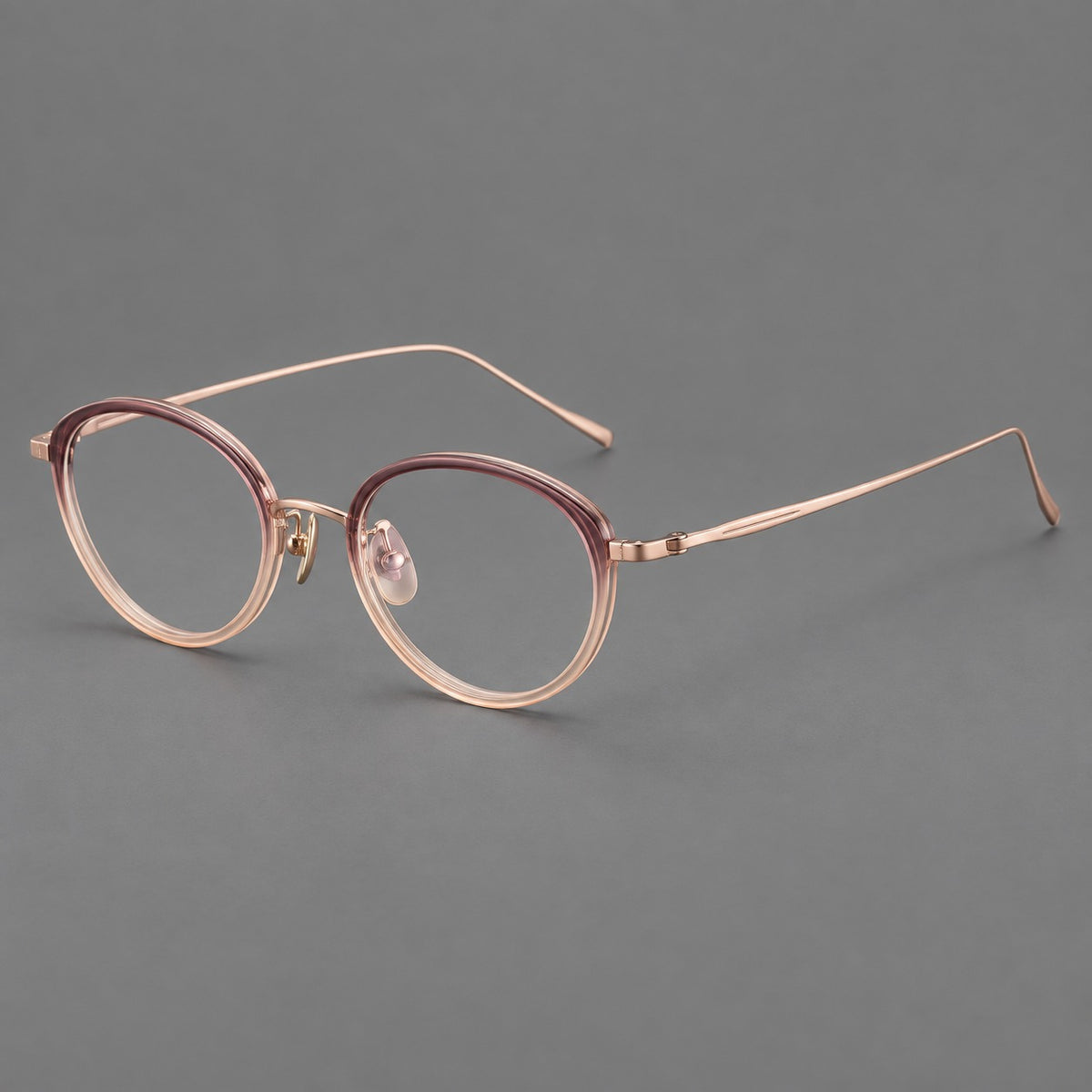 Round eyeglasses in acetate and titanium with a slim curved bridge and fine metal temples in Pink Tea Gradient / Rose Gold, three quarter view
