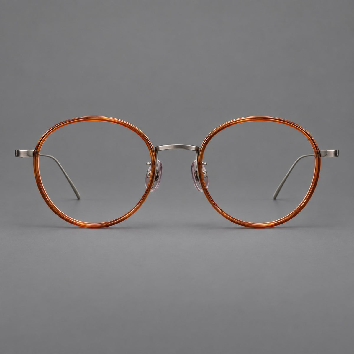 Classic round eyeglasses in acetate and titanium with slim rims and textured metal temples in Tea Brown / Gunmetal, front view