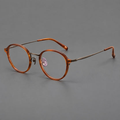 Softly rounded eyeglasses in acetate and titanium with a curved bridge and engraved temples in Tea Brown / Antique Bronze, three quarter view front view