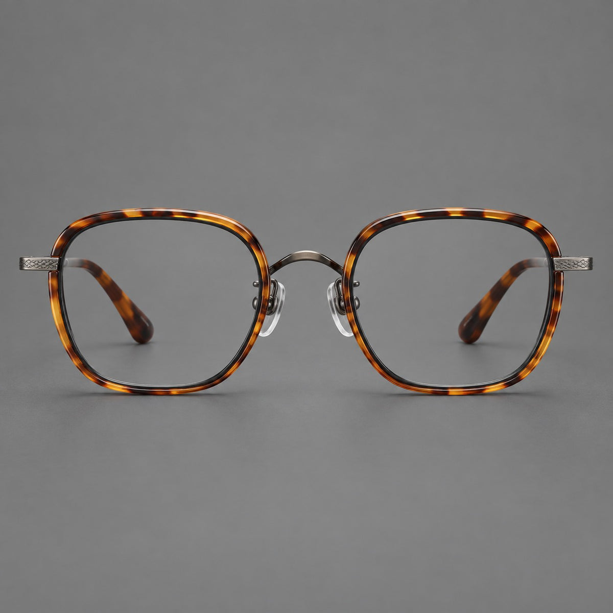Rounded square eyeglasses in acetate and titanium with an arched bridge and engraved temples in Amber Tortoiseshell / Gunmetal, front view
