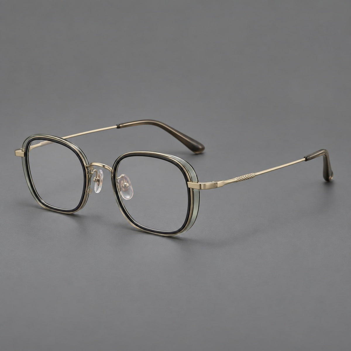 Rounded square eyeglasses in acetate and titanium with an arched bridge and engraved temples in Clear Tea Grey Green / Light Gold, three quarter view