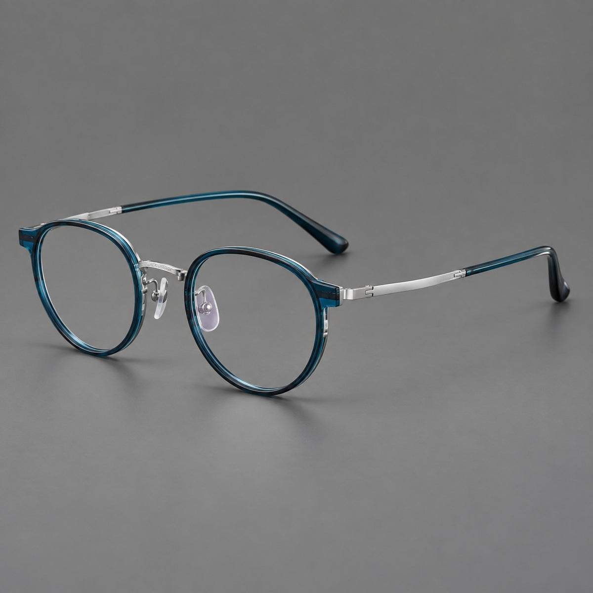 Round eyeglasses in acetate and titanium with widened outer corners and slender metal temples in Peacock Blue / Silver, three quarter view
