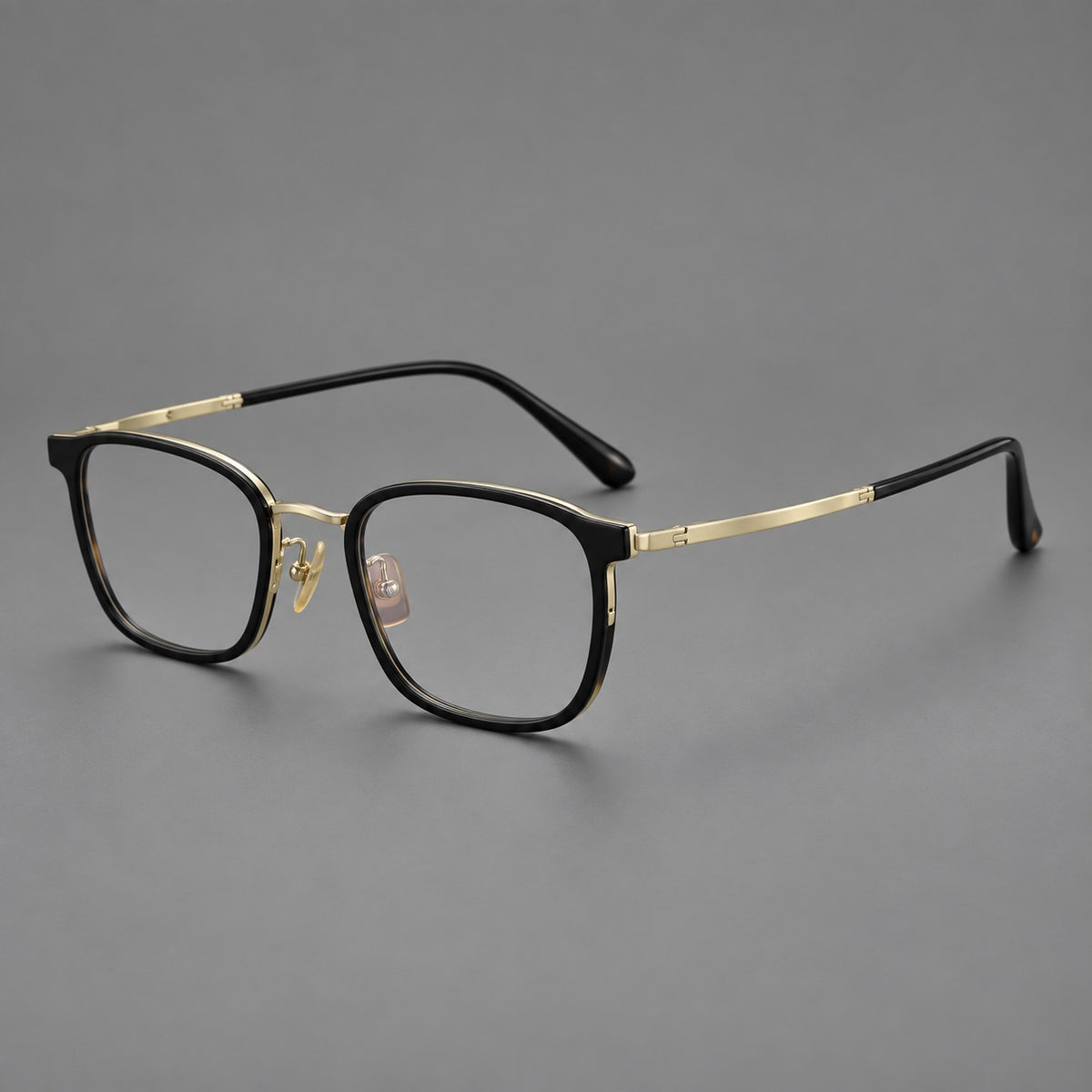 Rounded rectangular eyeglasses in acetate and titanium with bold corners and engraved metal temples in Glossy Black / Gold, three quarter view