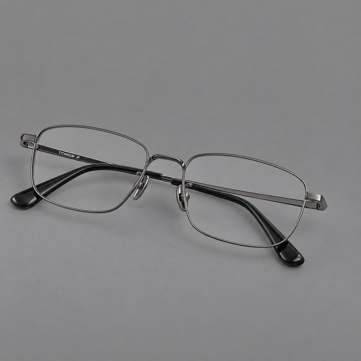 Modern square titanium glasses with an angular bridge and broad straight temples in Gunmetal, three quarter view