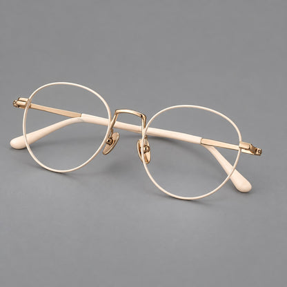 Retro round titanium glasses with a raised bridge and smooth corner shoulders in Cream and Gold, three quarter view lens detail