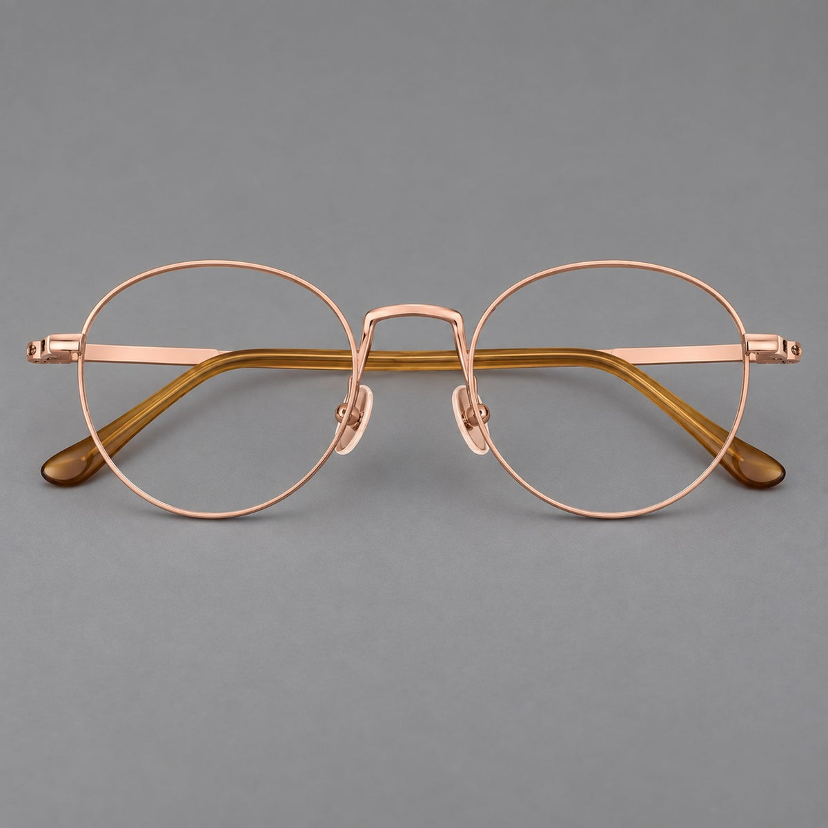 Retro round titanium glasses with a raised bridge and smooth corner shoulders in Rose Gold, front view