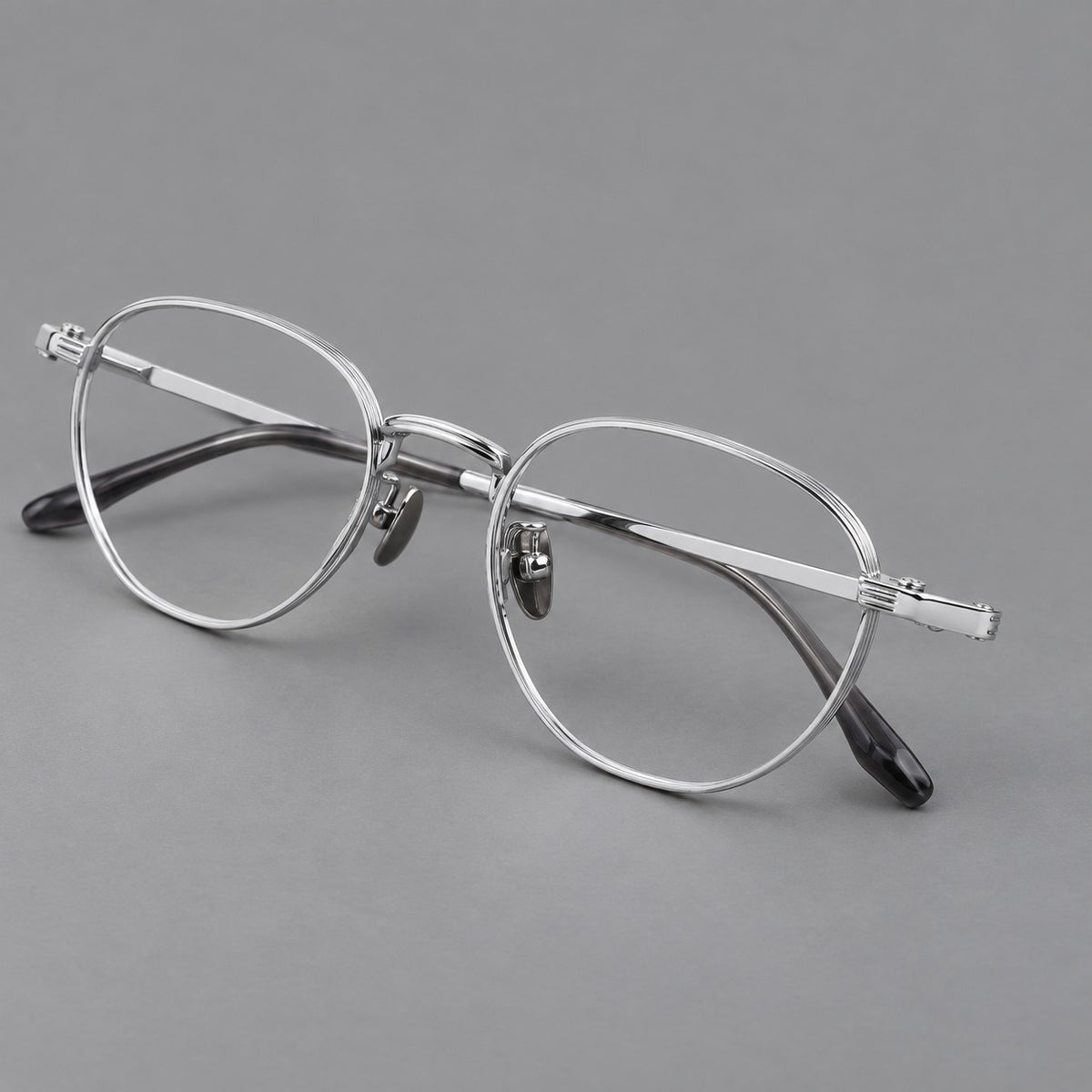 Retro panto titanium glasses with a curved bridge and fine parallel rim grooves in Silver, three quarter view