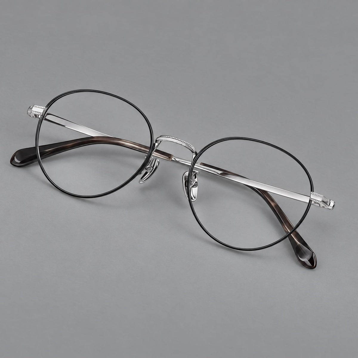 Rounded panto titanium glasses with a raised bridge and dotted temple accents in Black and Silver, three quarter view