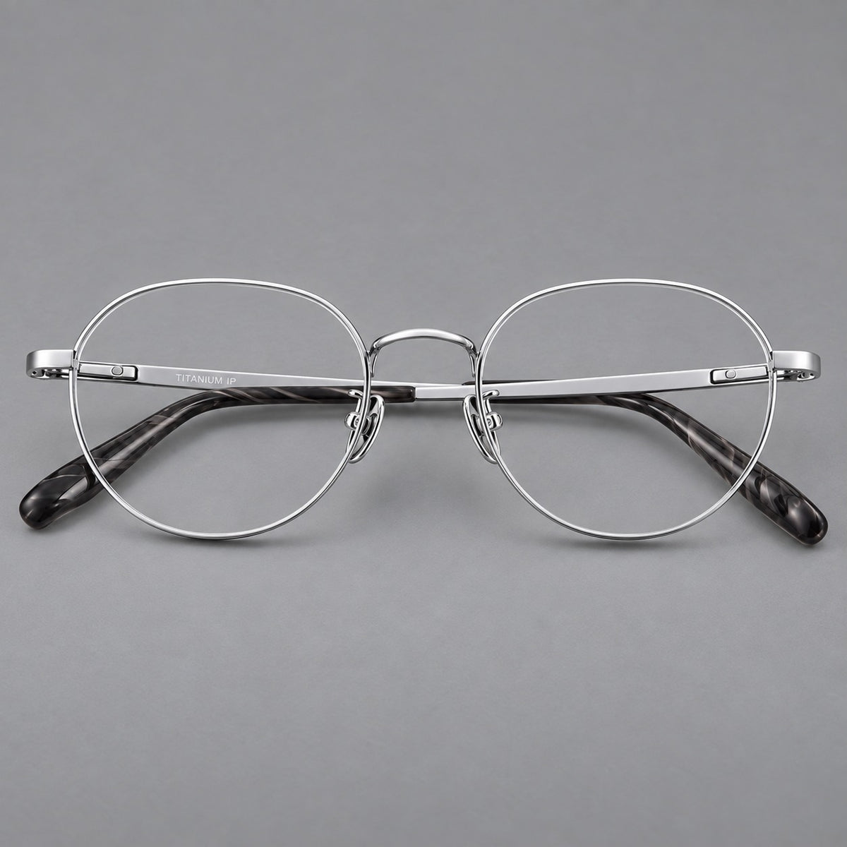 Classic round titanium glasses with broad flat temples and inset hinge details in Silver, front view