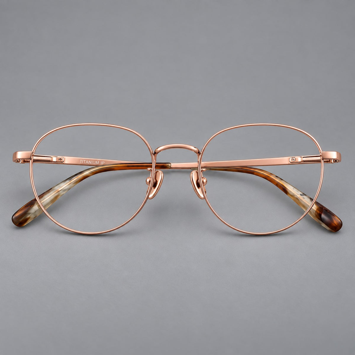 Classic round titanium glasses with broad flat temples and inset hinge details in Rose Gold, front view