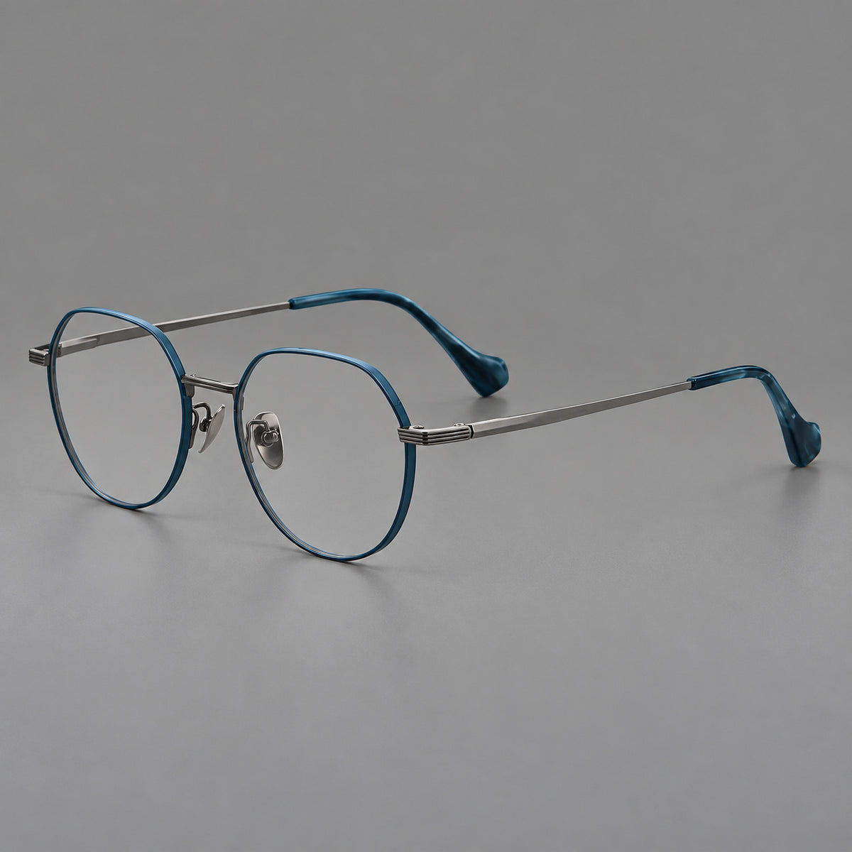 Geometric titanium glasses with soft polygonal rims and fine shoulder detailing in Blue and Gunmetal, three quarter view