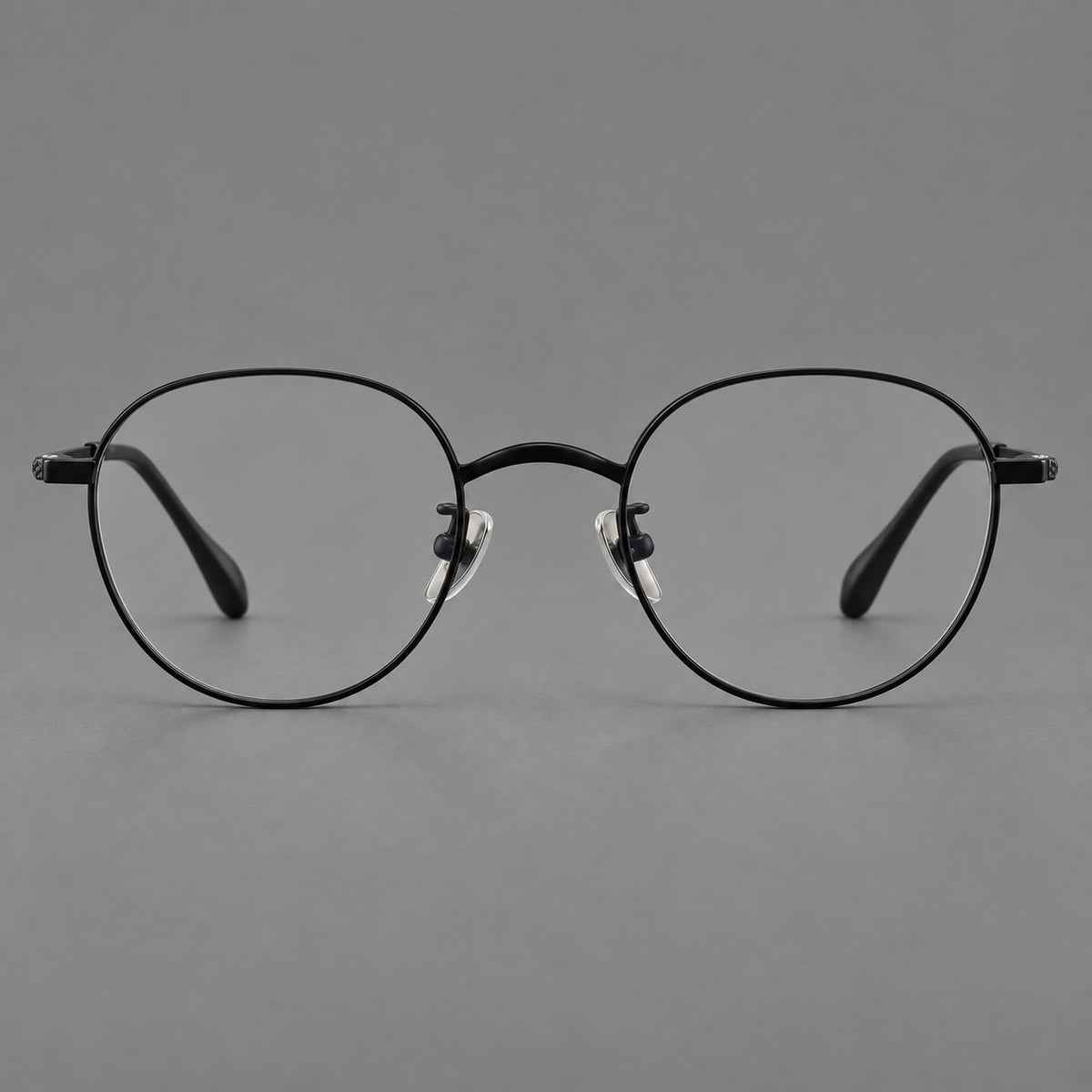 Compact round titanium glasses with an arched bridge and textured temple accents in Black, front view