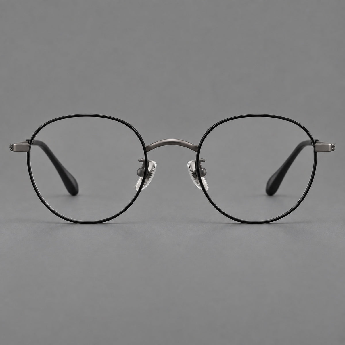 Compact round titanium glasses with an arched bridge and textured temple accents in Black and Gunmetal, front view