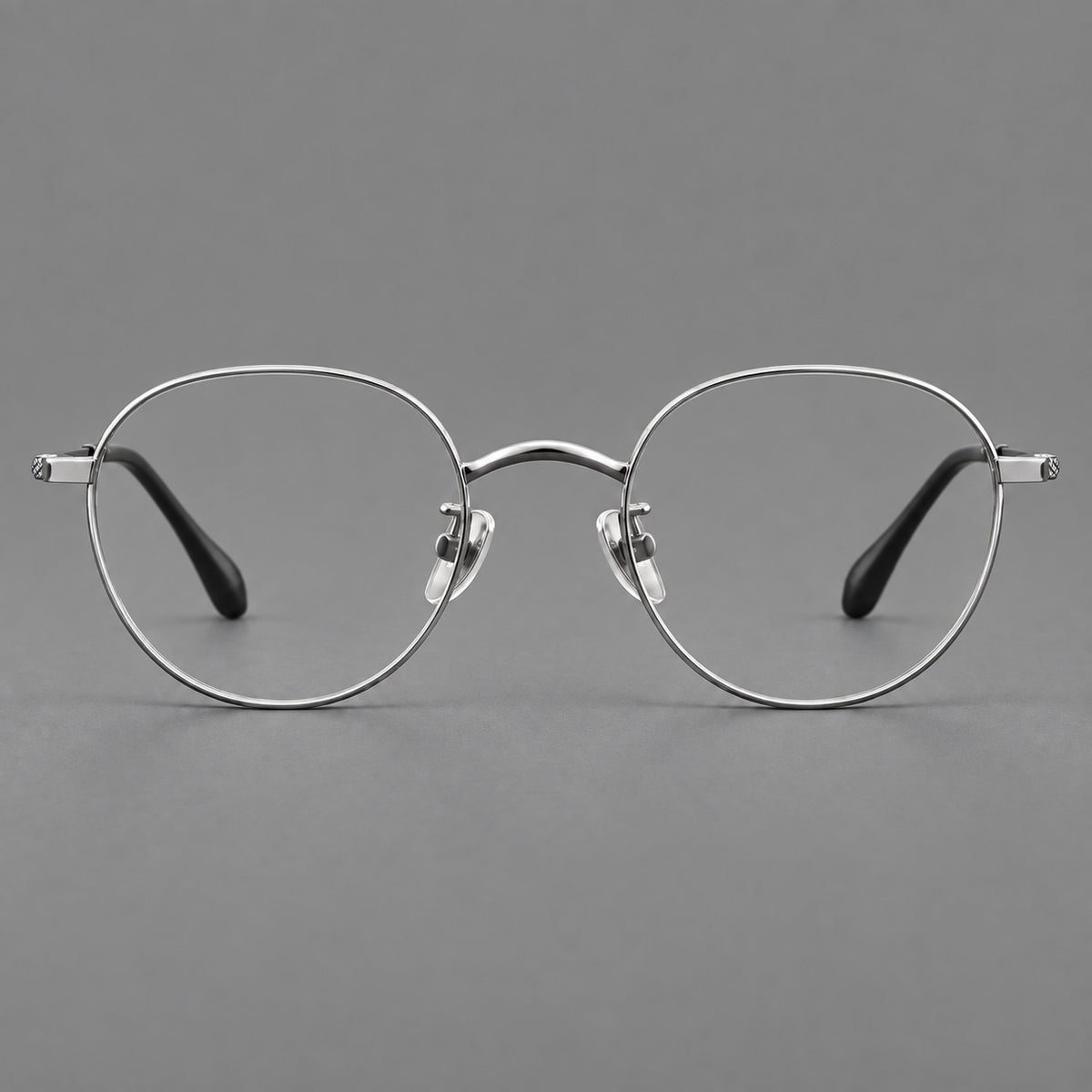 Compact round titanium glasses with an arched bridge and textured temple accents in Silver, front view