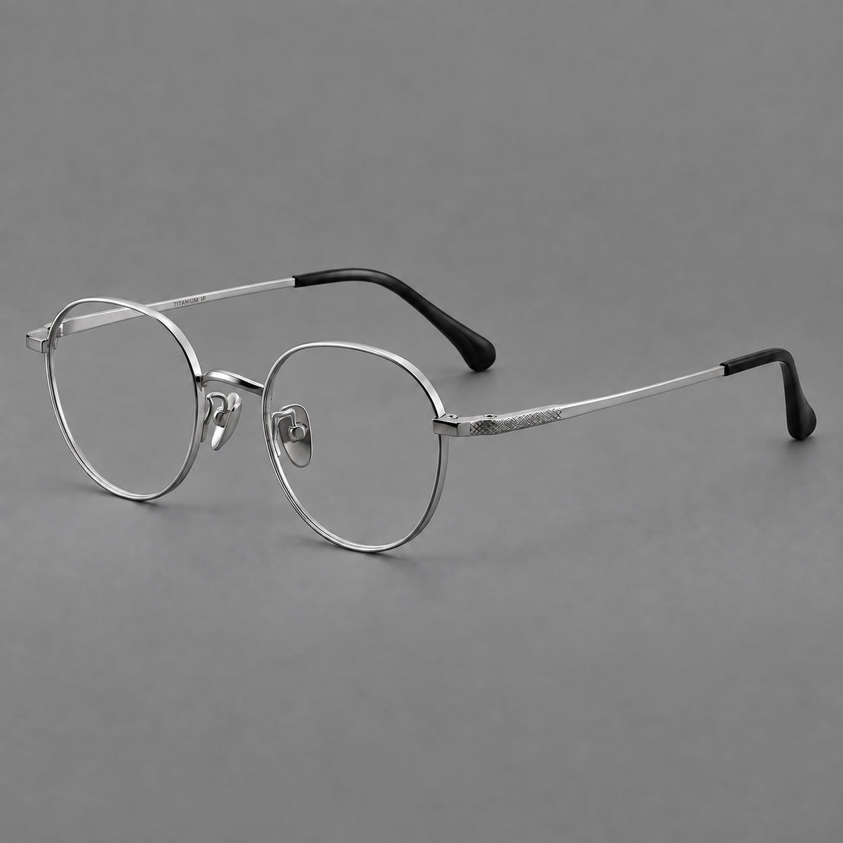 Compact round titanium glasses with an arched bridge and textured temple accents in Silver, three quarter view