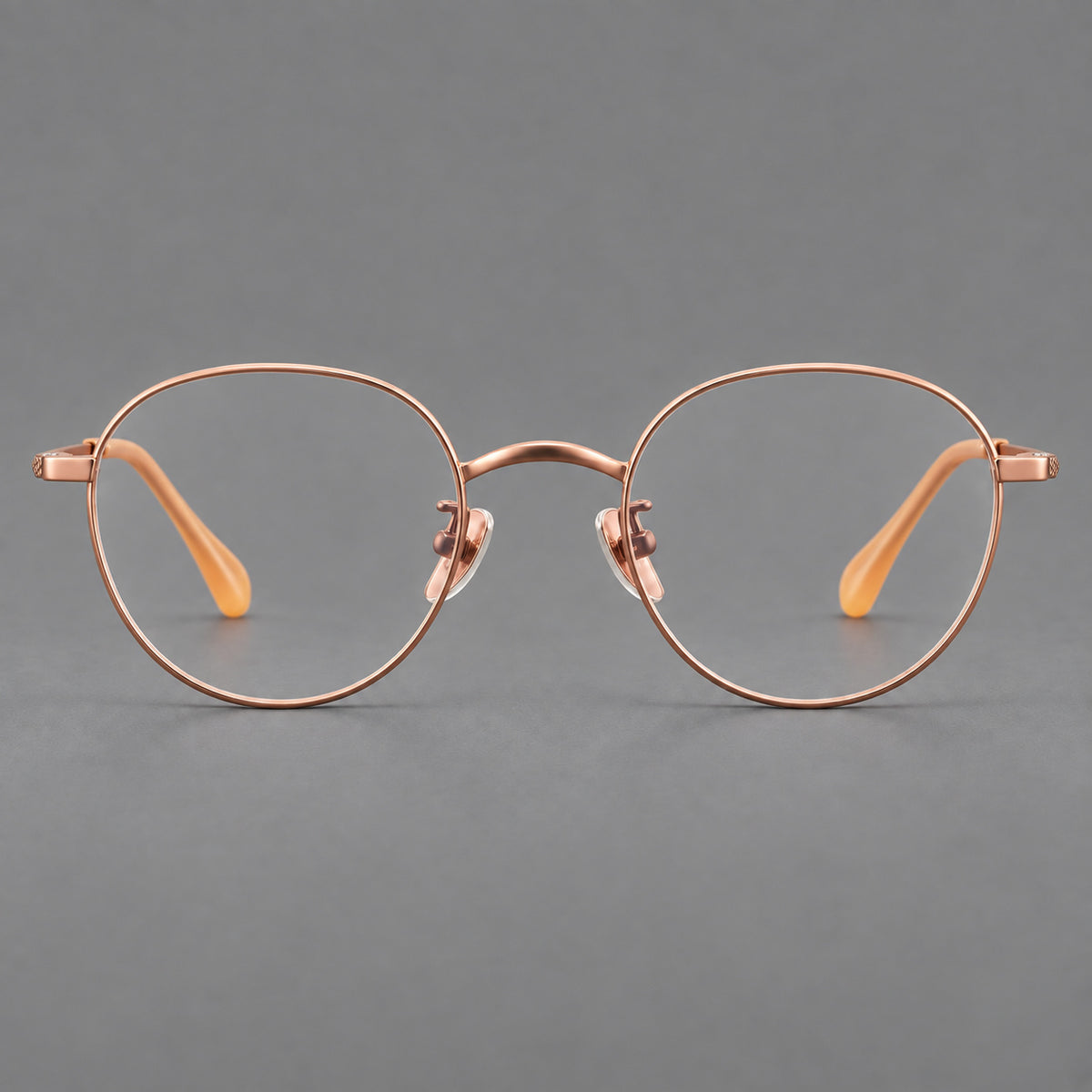 Compact round titanium glasses with an arched bridge and textured temple accents in Rose Gold, front view