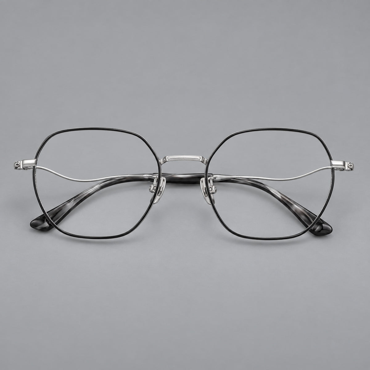 Geometric titanium glasses with engraved rim edges and curved temple joins in Black and Silver, front view