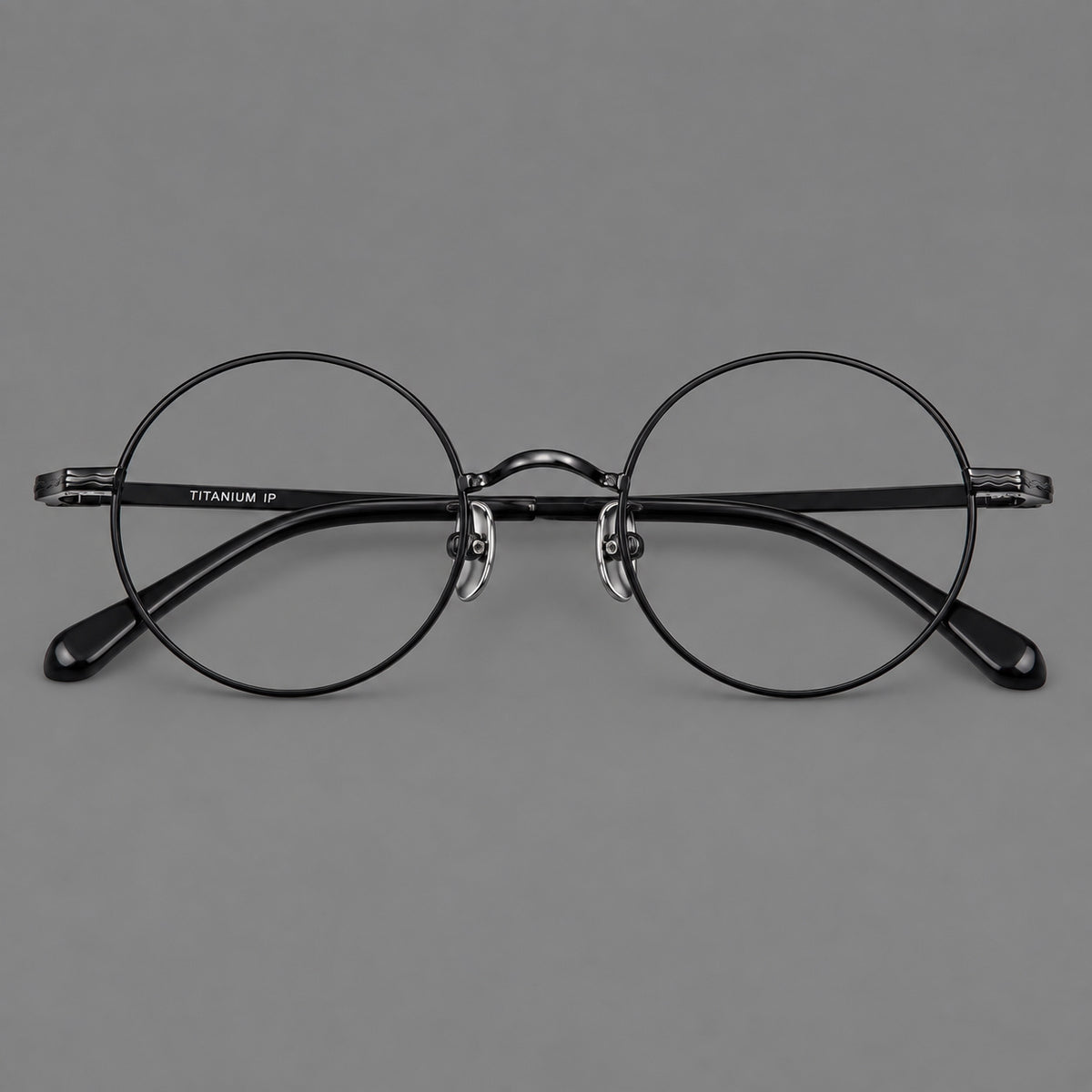 Compact circular titanium glasses with a curved bridge and wavy engraved temples in Black, front view