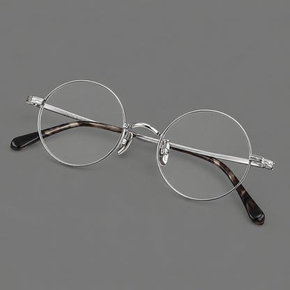 Compact circular titanium glasses with a curved bridge and wavy engraved temples in Silver, three quarter view lens detail