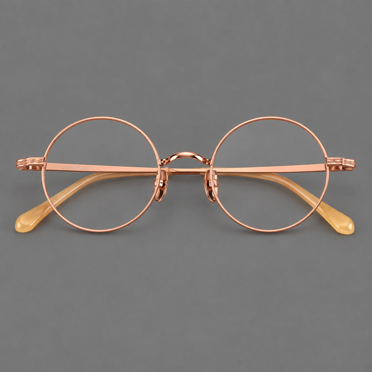 Compact circular titanium glasses with a curved bridge and wavy engraved temples in Rose Gold, front view