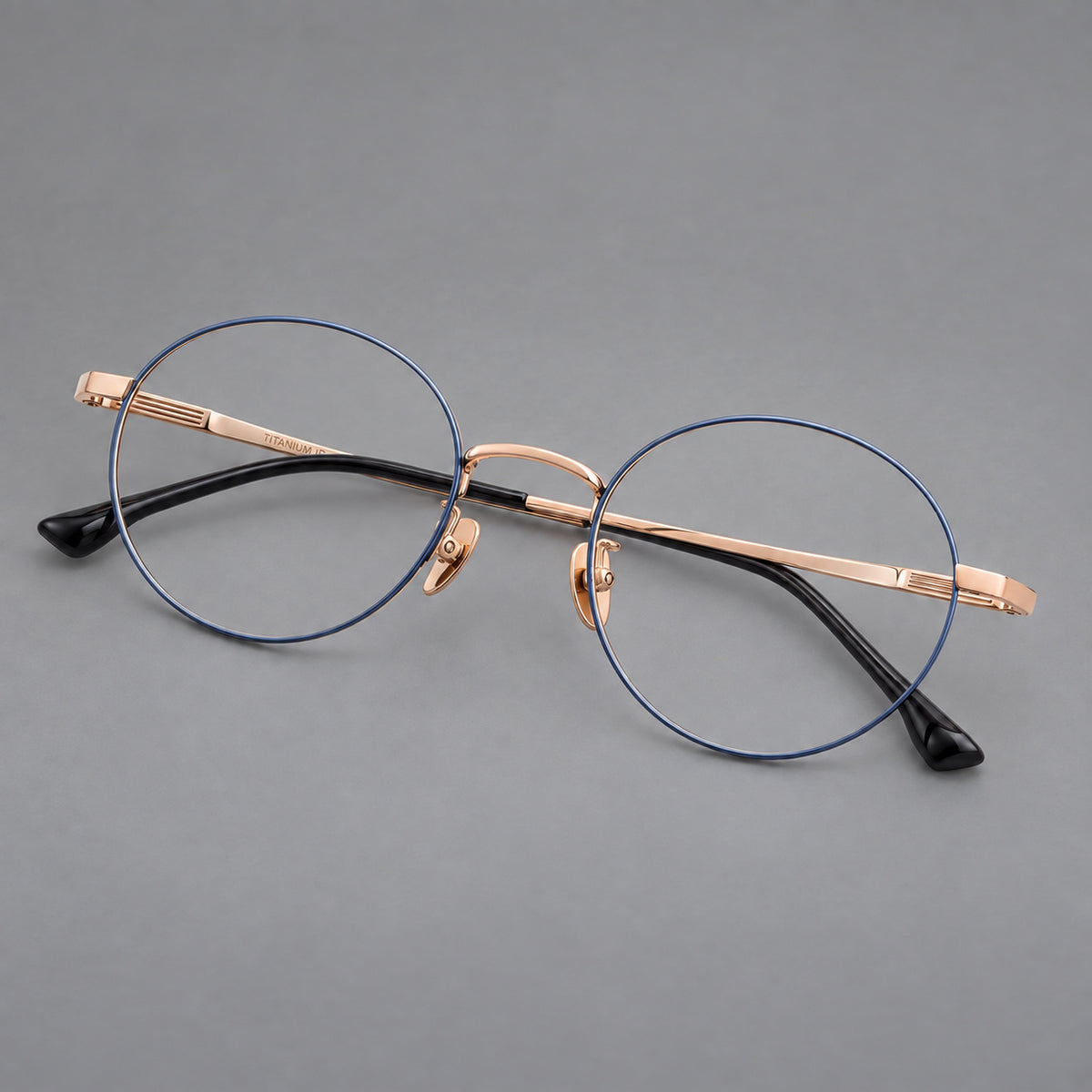 Classic circular titanium glasses with a raised bridge and lined temple accents in Blue and Gold, three quarter view