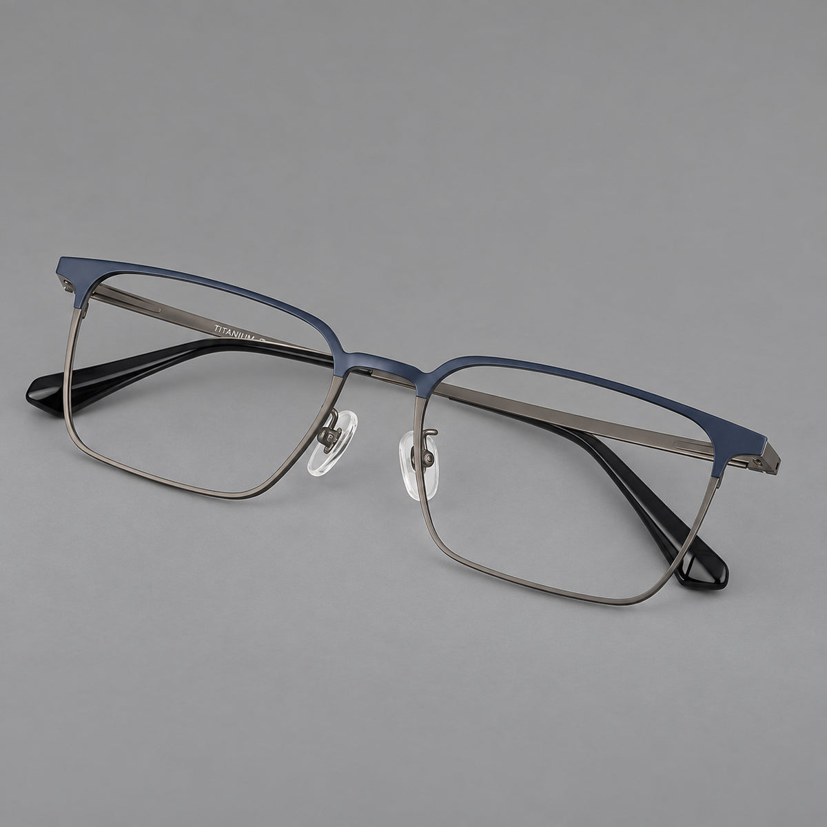 Bold rectangular titanium glasses with strong upper corners and flat metal temples in Blue and Gunmetal, three quarter view